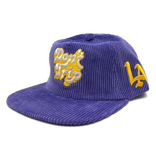 Don't Trip purple corduroy hat with white and yellow embroidered Don't Trip logo and yellow LA logo on a white background, front - Free & Easy